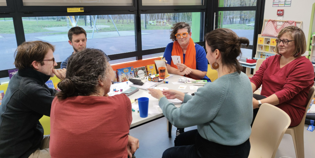 Formation serious game design - groupe de participants autour d'une table avec jeux pédagogiques